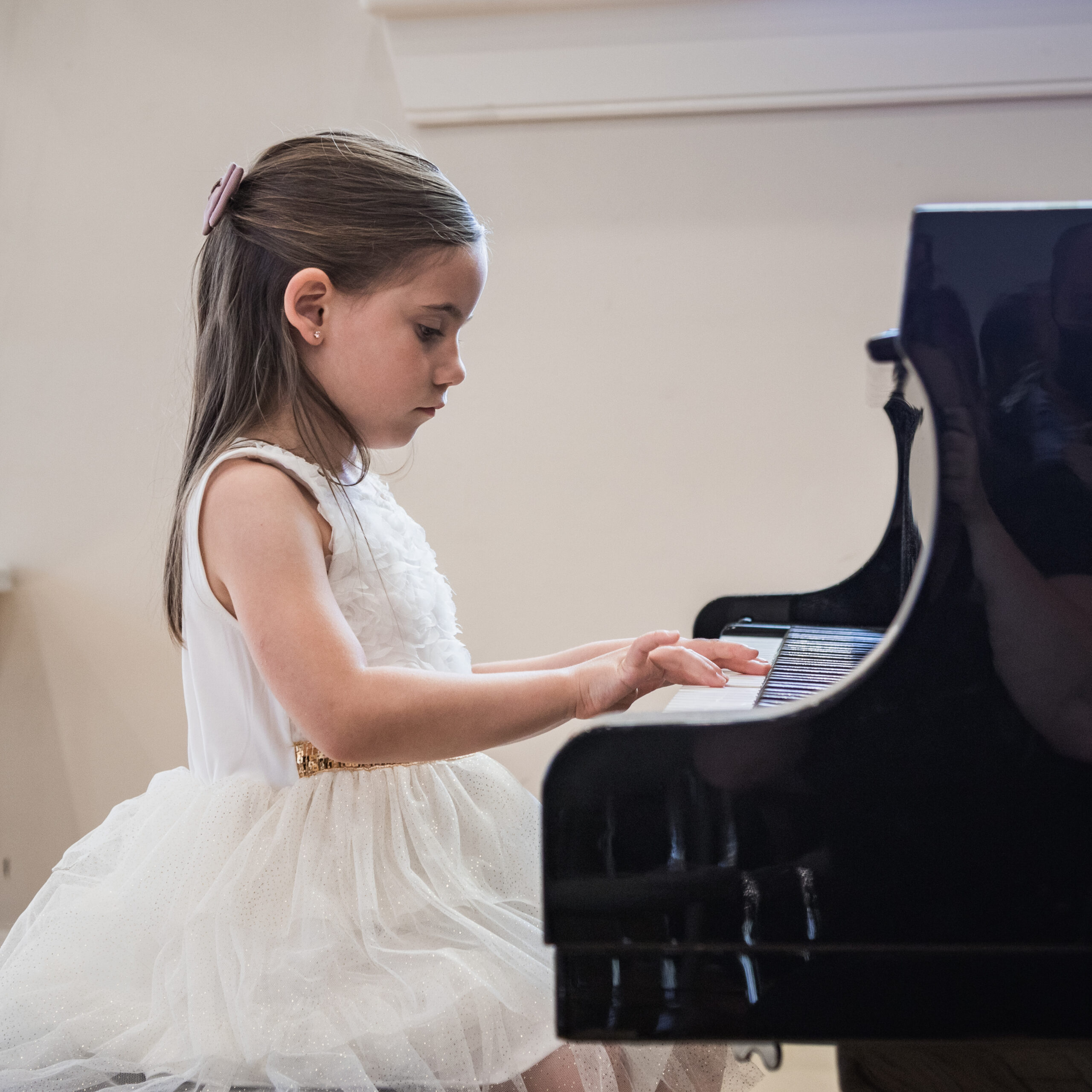 Young girl playing piano in white dress